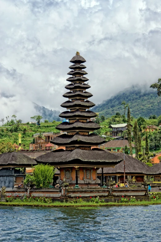 an ornate building sits by the water with people walking about