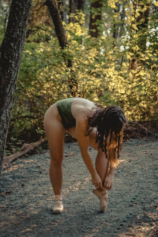 a man with dreadlocks in the woods bending over