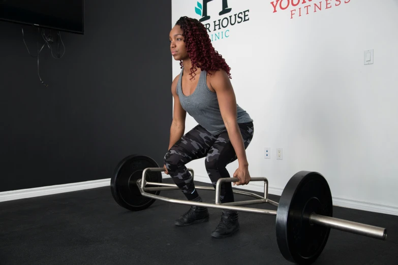 woman lifting barbells in front of wall for crossfit