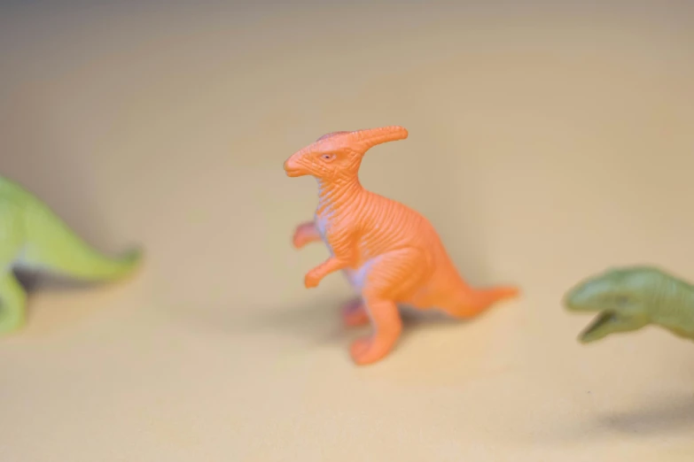 four dinosaur toys are lined up on a table