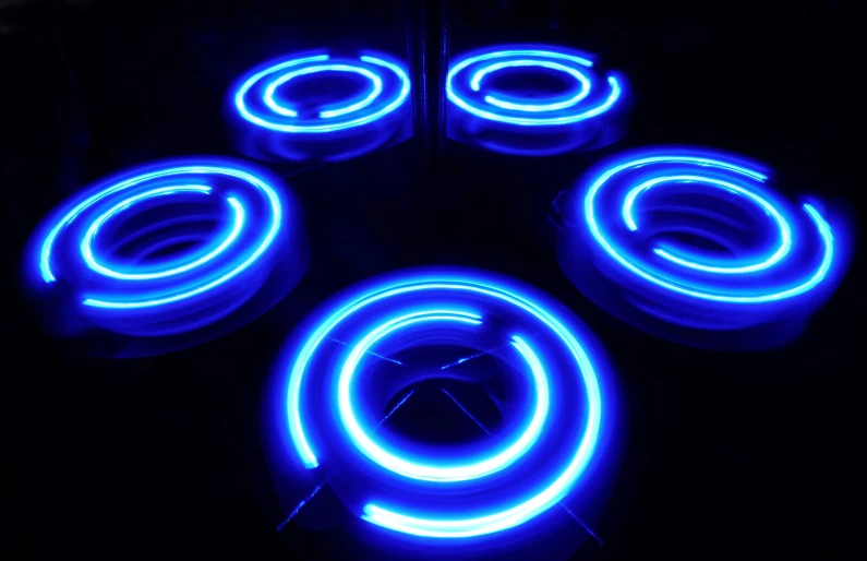 four blue rings of neon lights on a dark surface