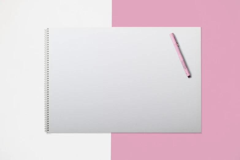notebook with a pink pen lying on it on a bright pink background