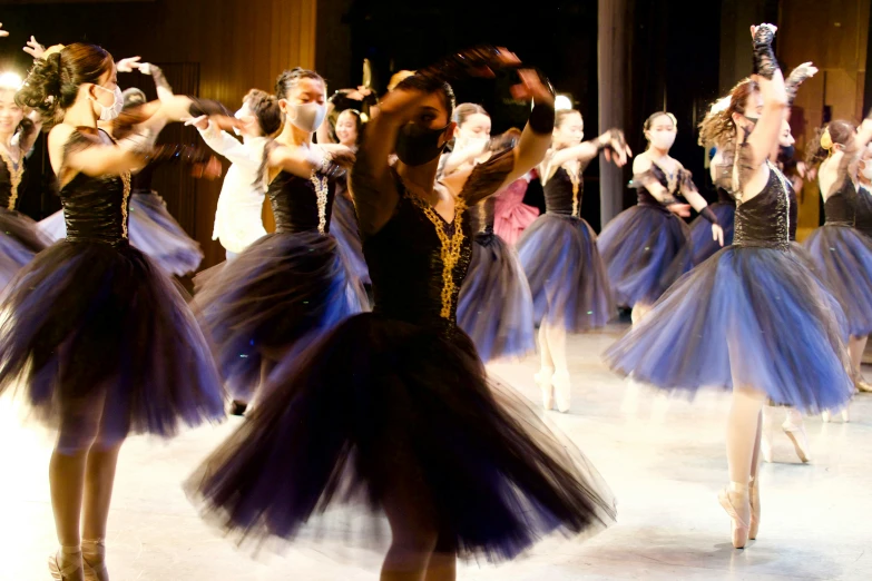 several ballerinas in tutu skirts move around on the floor