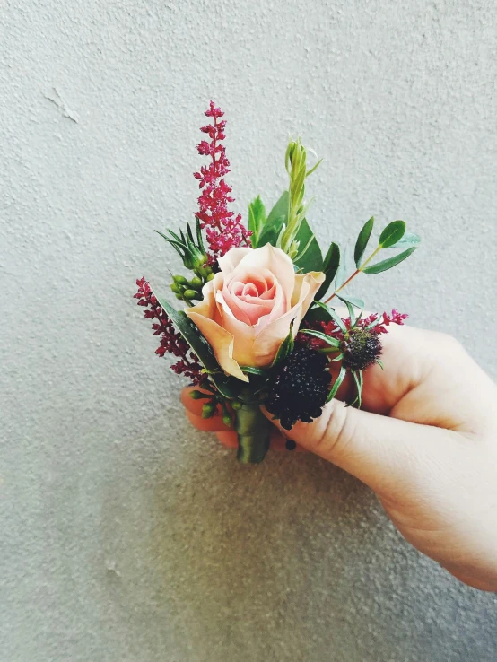 a hand is holding a fake rose with flowers