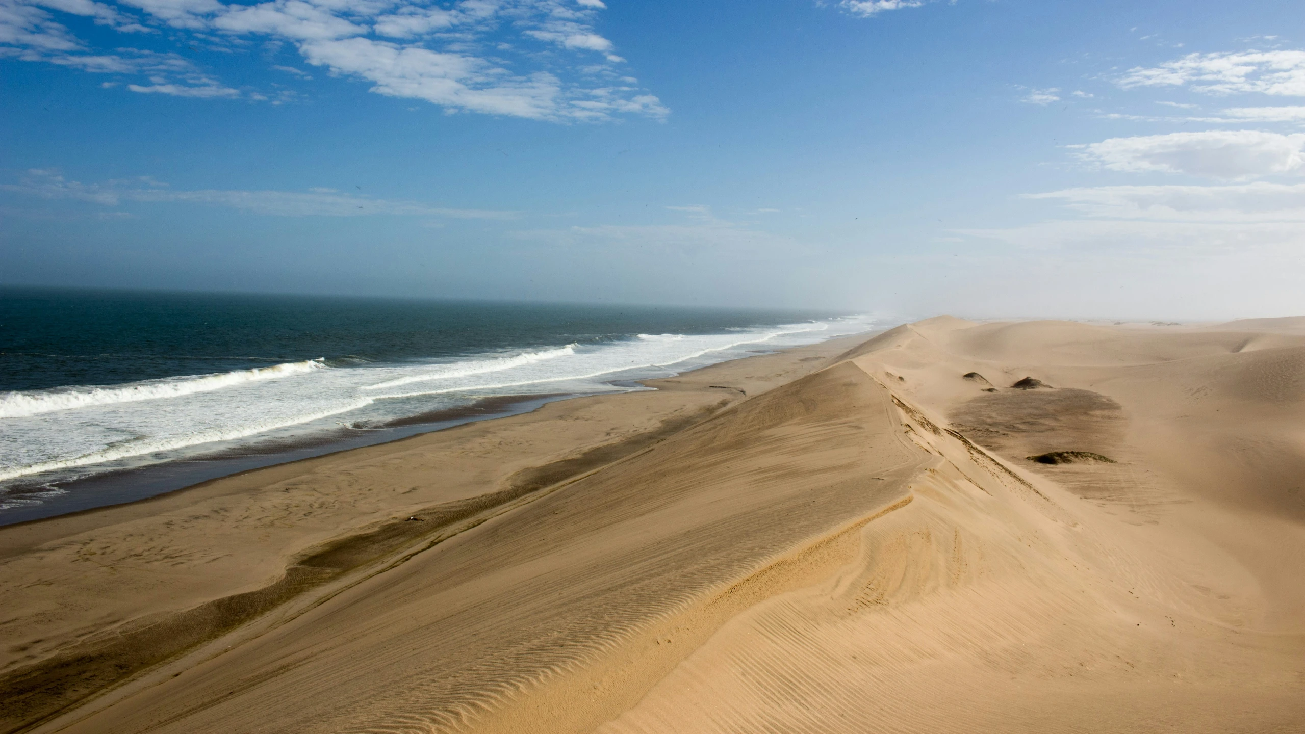 a plane flying over a large sandy desert with waves