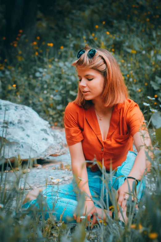 young woman sitting in front of rocks and flowers