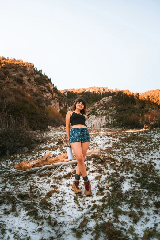 a young woman wearing short shorts, standing on a beach