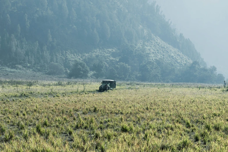 two pickup trucks driving down a large grass covered field