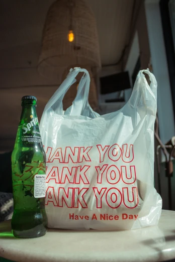 a bottle and a bag sitting on a table with the words thank you
