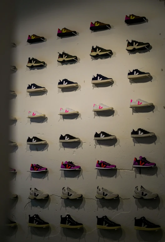 the wall has many pairs of sneakers in it