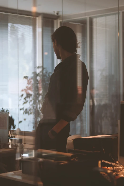 a blurry image of a woman in an office looking out the window