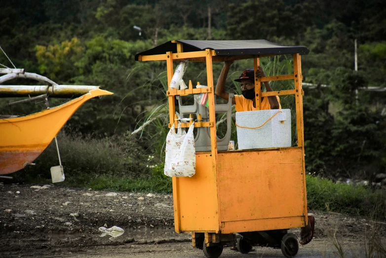 a man is sitting in a yellow cart by a body of water