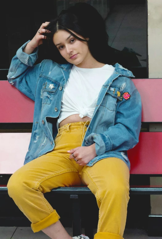 a woman in yellow pants sitting on a bench