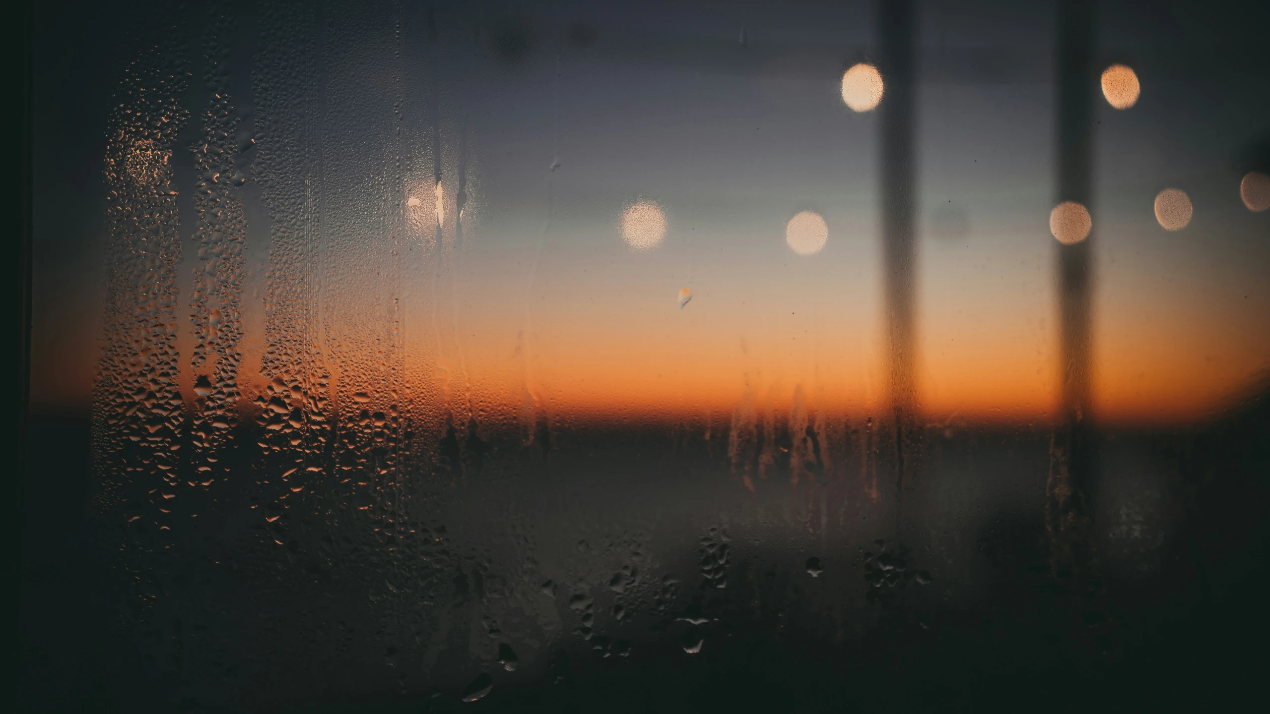 rain drops are visible on a window at sunset