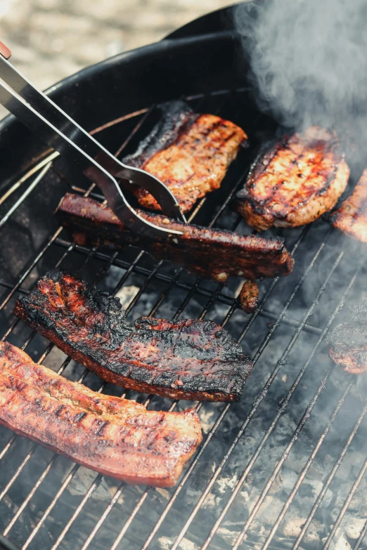 several strips of ribs on a grill with a fork