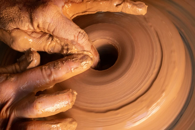 hands throwing a bowl on a pottery wheel