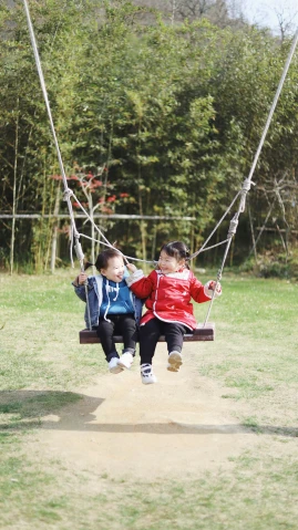 two young children playing on a swings set