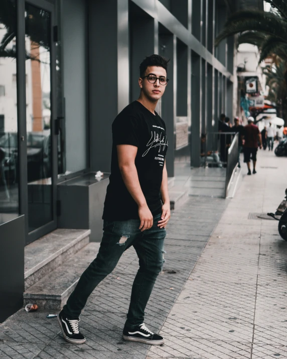 a man is walking down a sidewalk wearing glasses