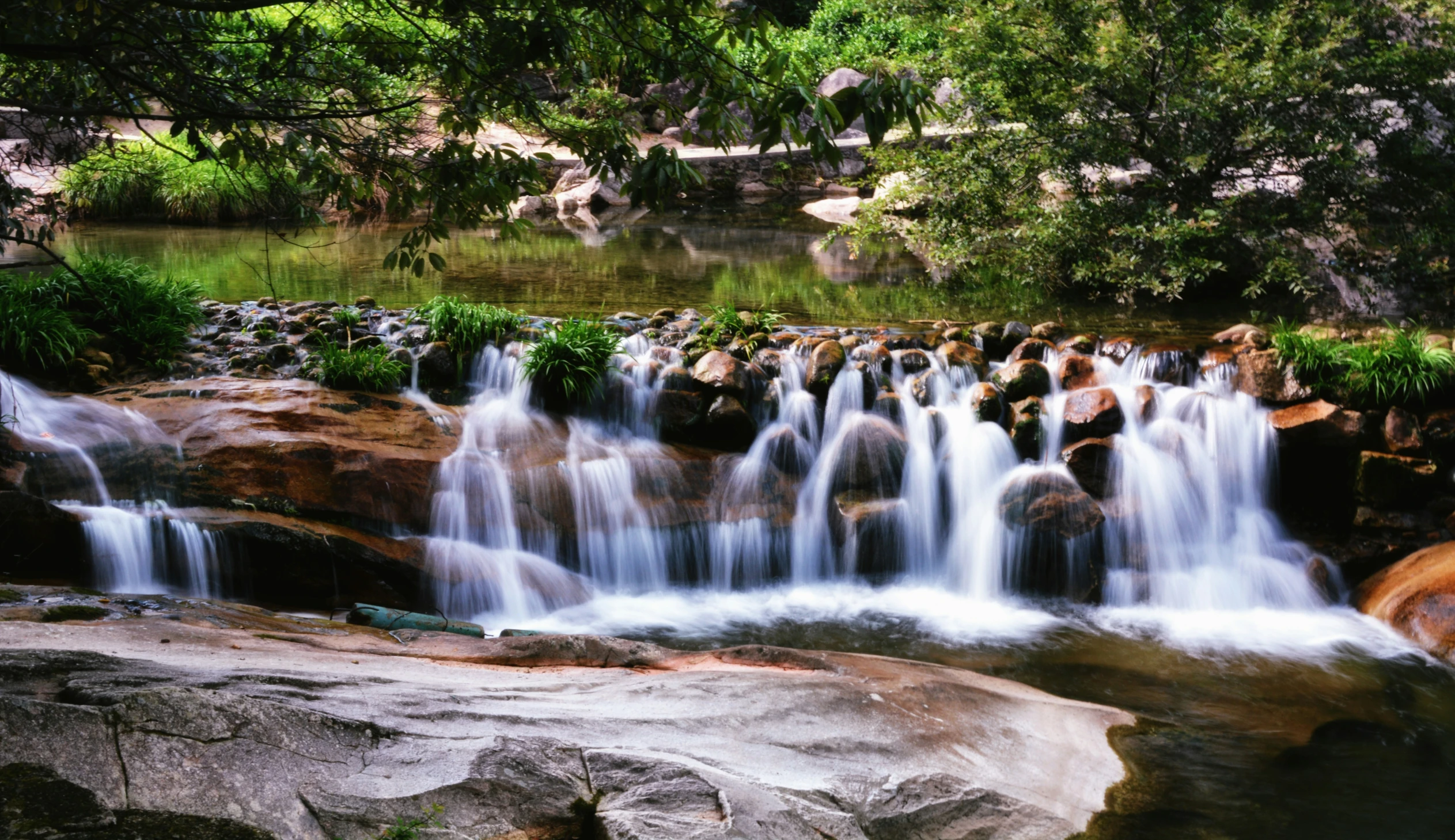 water falling off of a rocky surface into a pool of water