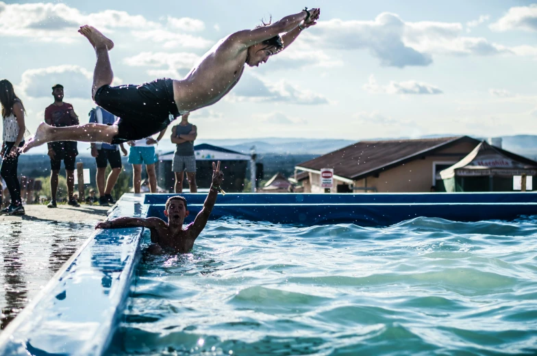 a man diving off of a boat into a body of water