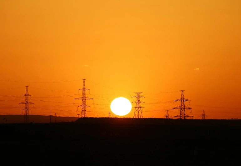 the sun is setting behind power lines and towers