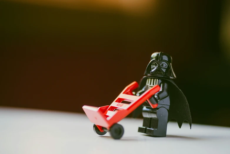 a lego toy with a star wars darth vader hing a cart