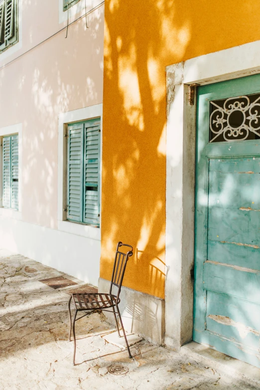 an empty chair sits near a door on the sidewalk