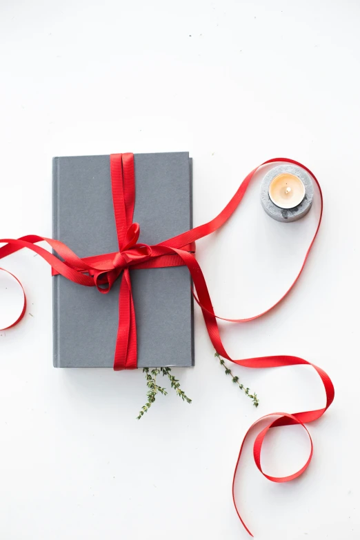 a grey box tied with red ribbon and a small candle