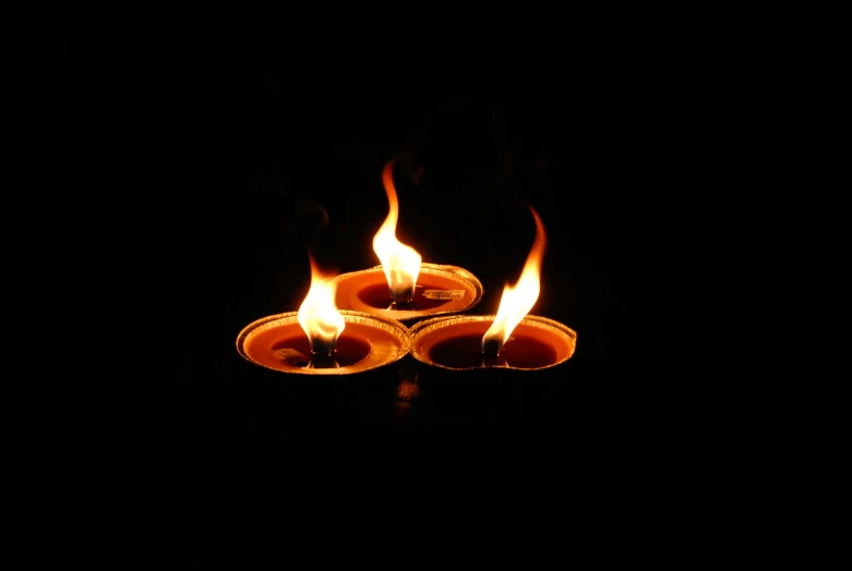 candles lit in a circle shaped flame on dark background