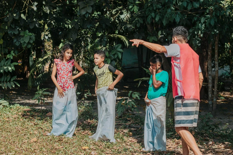 several young people stand on grass near some trees