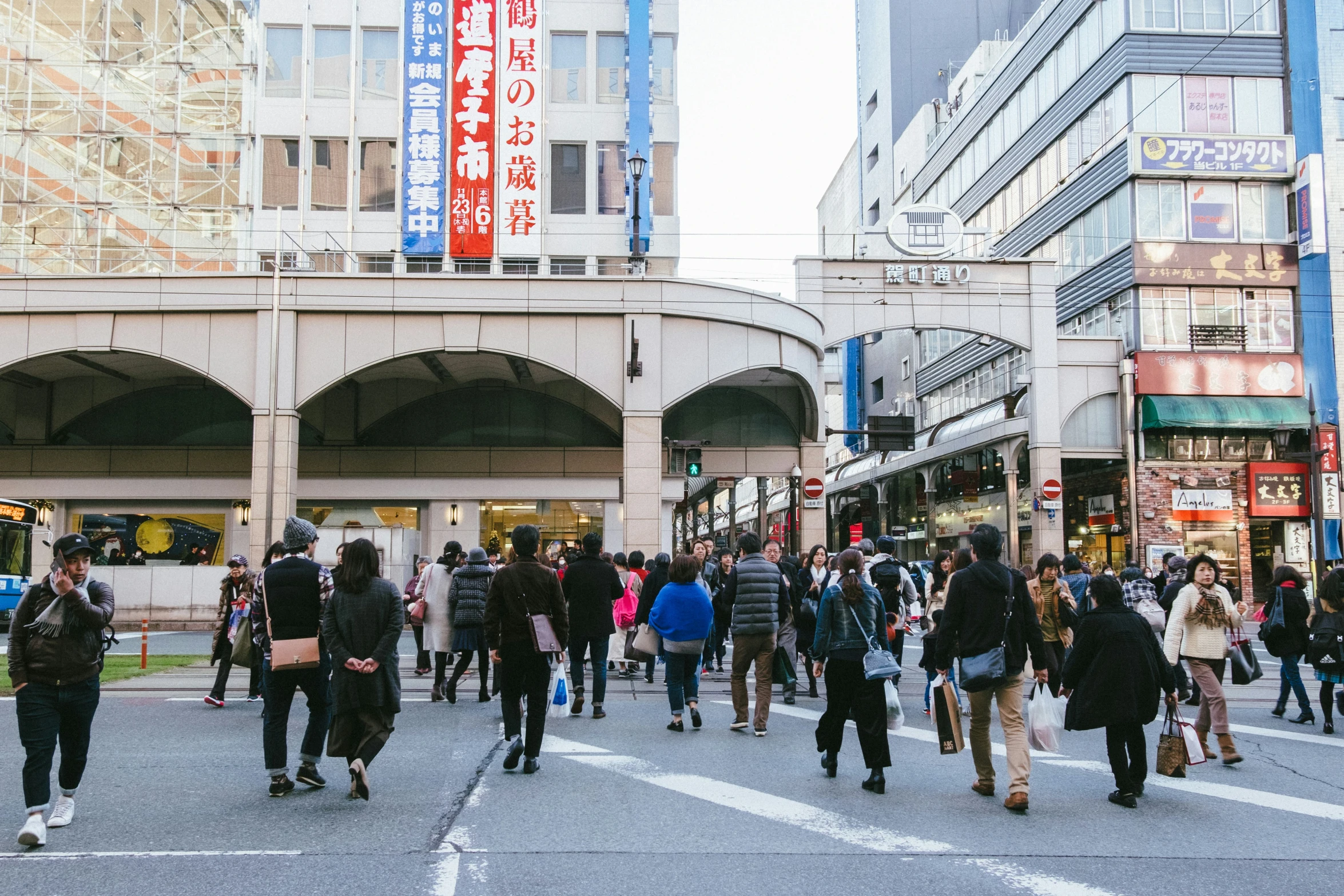 this crowd is crossing the street at a busy intersection