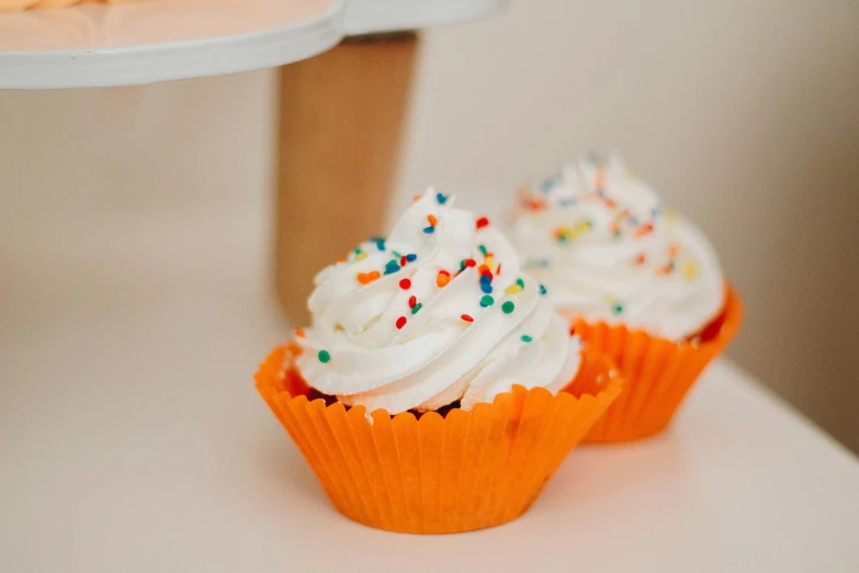 a couple cupcakes with white frosting and sprinkles on the rim
