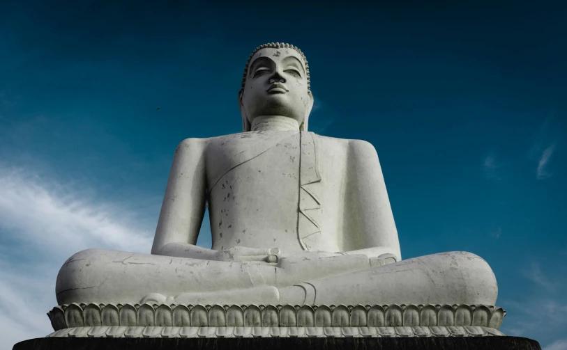 large statue of a man sitting in meditation position with his hand under his chin