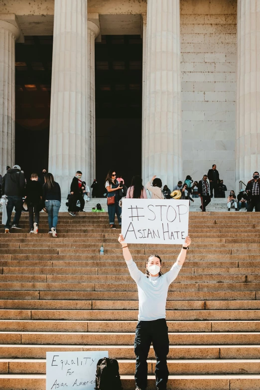 man holding up a sign while standing on steps outside an old building