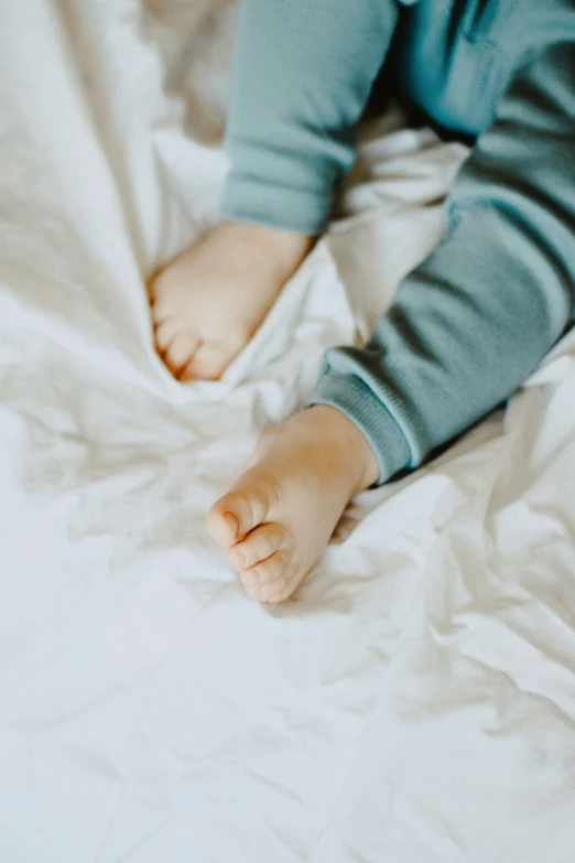 child laying down on a white bed in a bedroom