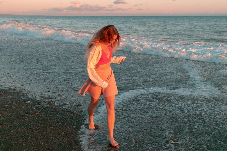 the girl is walking on the shore using her phone