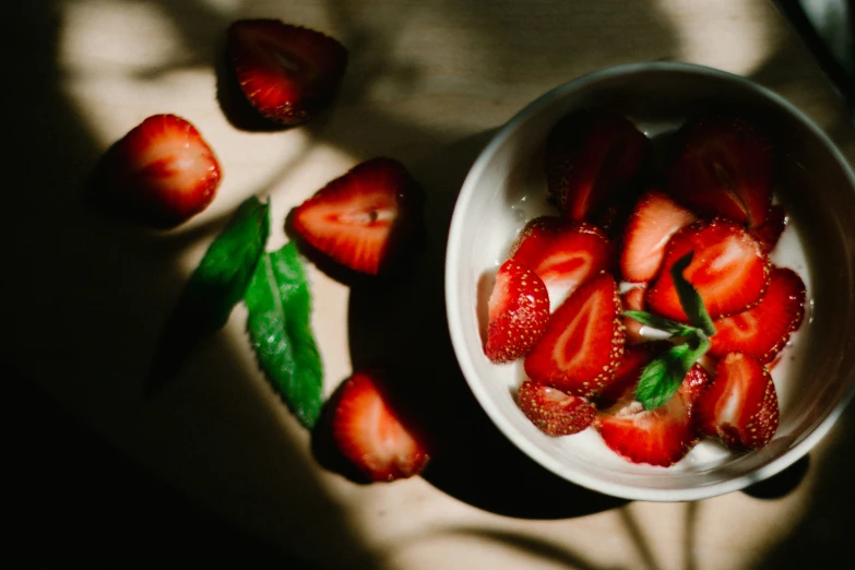 small bowls full of strawberries sit in a sunlit spot