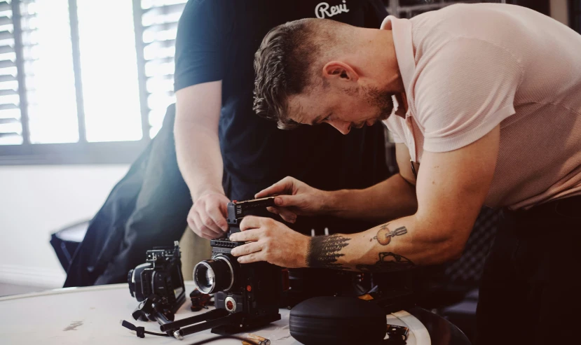 there is a man fixing a camera on the table