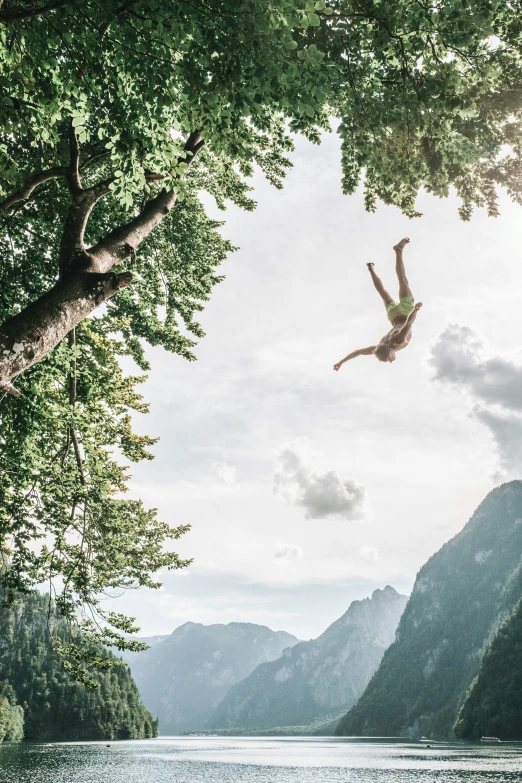 a woman floating in the air next to a river