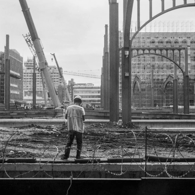 man standing in front of construction site while looking over fence