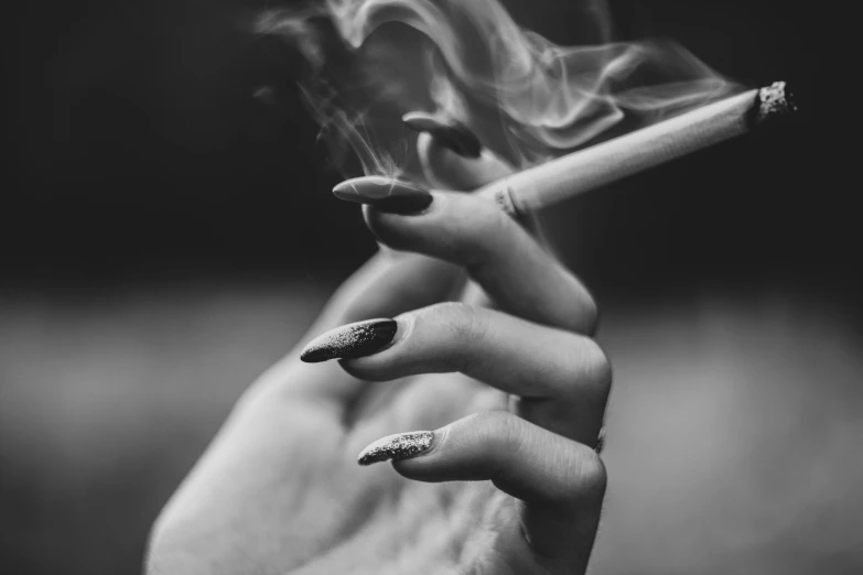 black and white pograph of hand holding out a cigarette