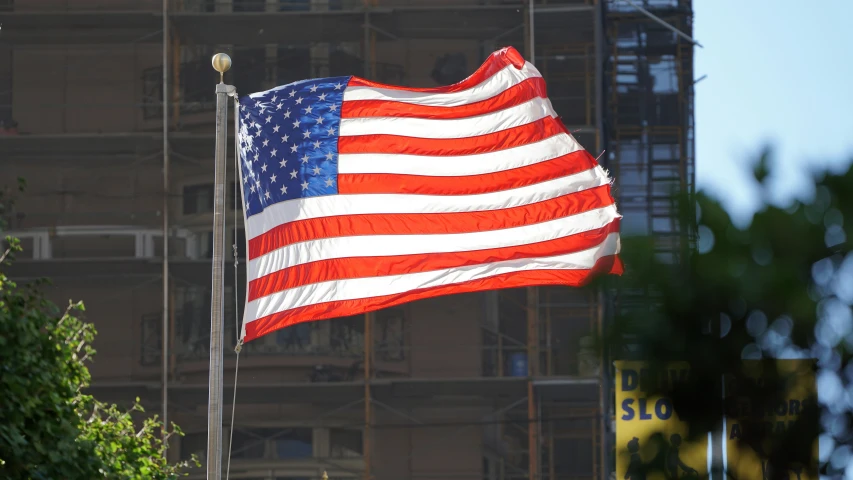 the american flag waving in front of a building with balconies