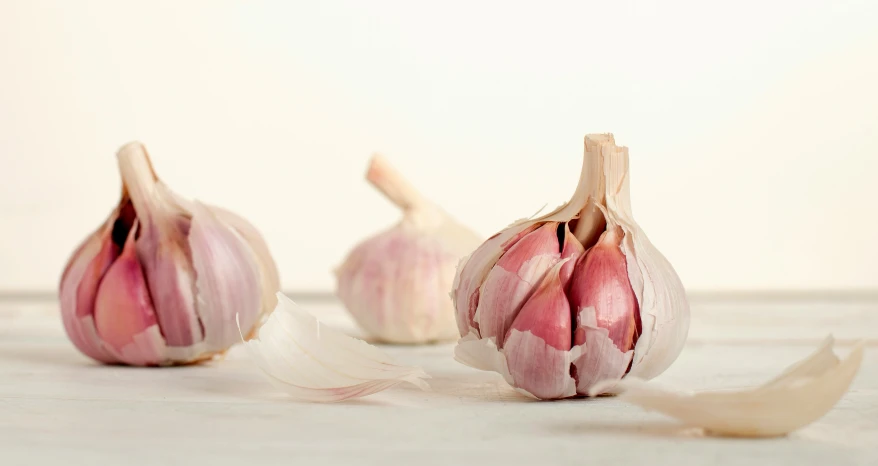 closeup of two garlic cloves and one broken in half