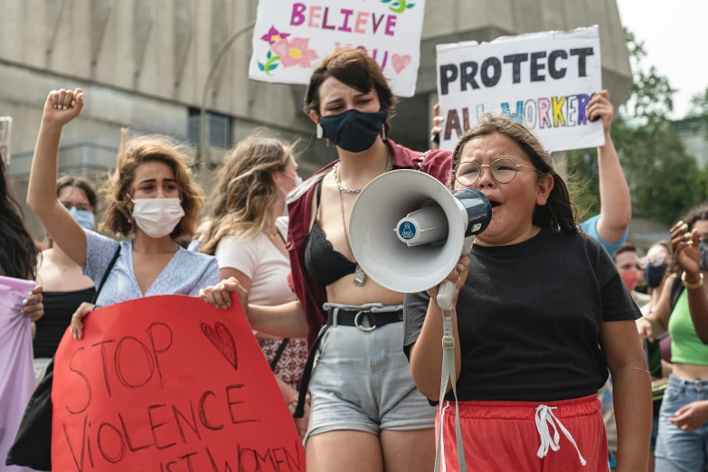 a group of protesters wearing face masks holding placards and a megaphone