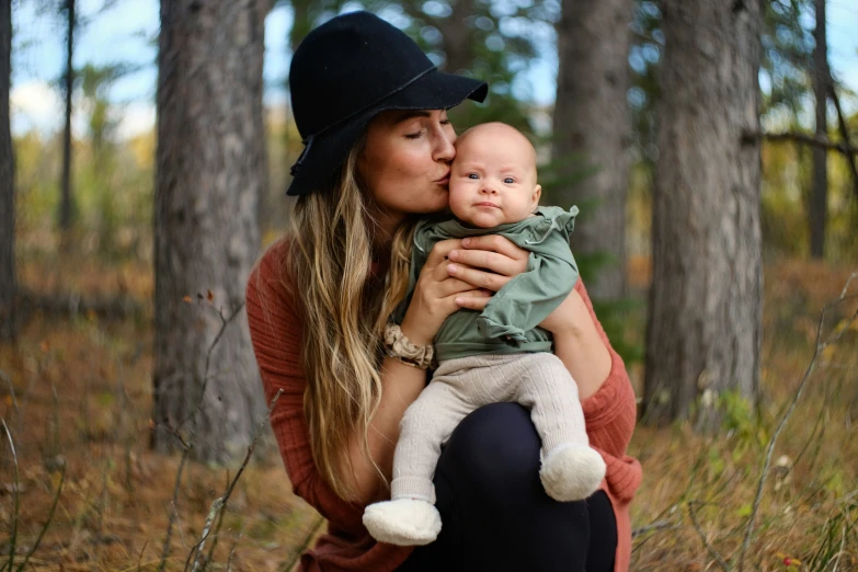 mother holding child while posing for po in woods