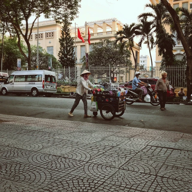 a person hing a cart down a street with two people on the other side