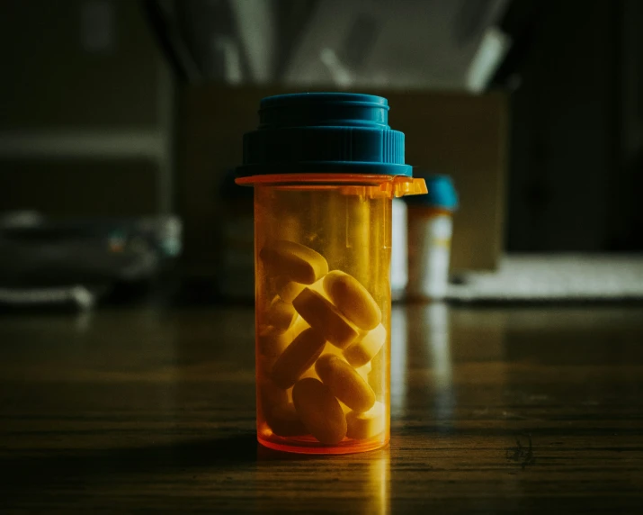 a bottle filled with orange pills on top of a table