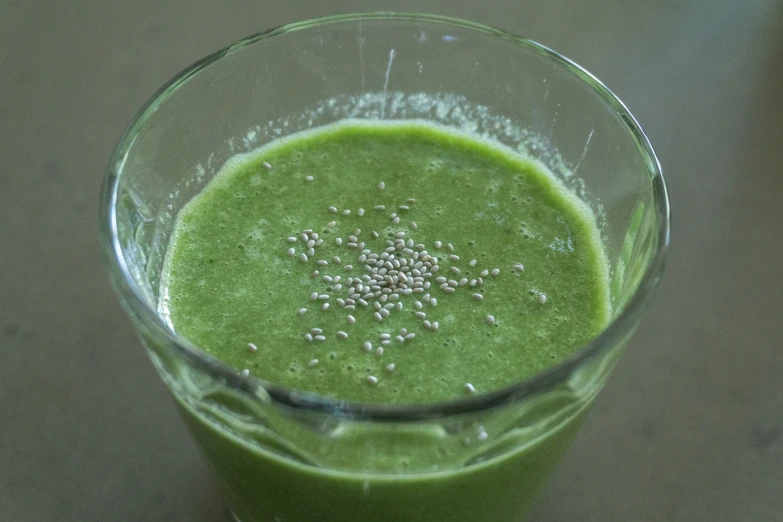 a glass filled with a green liquid on top of a counter