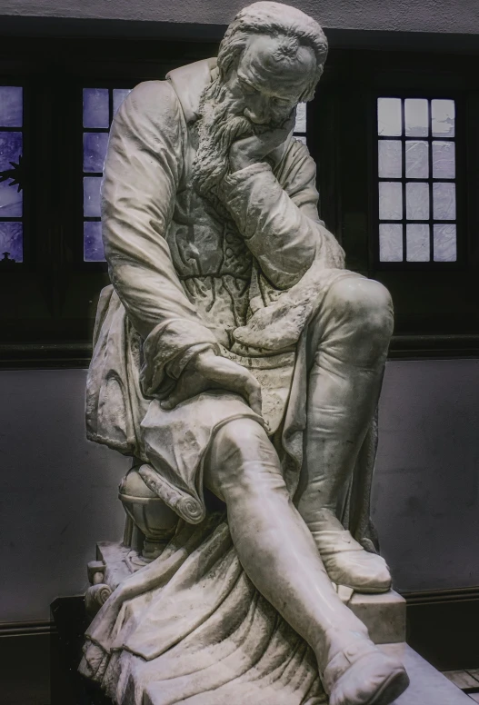 a sculpture of a man sitting with his hands behind his head