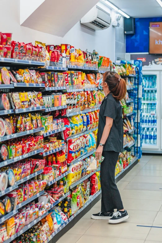 woman standing in a market aisle shopping for foods